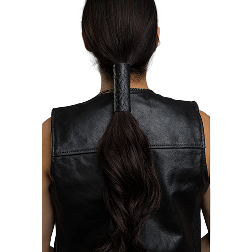 A person wearing a black leather hair glove with a debossed flames pattern.