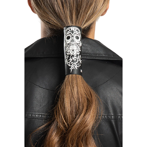 A person with a tribal skull patterned hair glove in black color, worn on a ponytail, against a black leather jacket background.