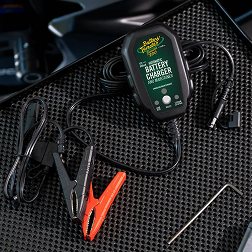 Battery Tender battery charger on a textured black surface with clamps attached.