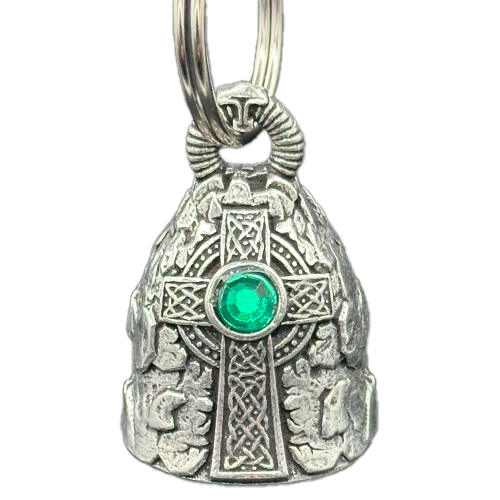 A Celtic cross-shaped motorcycle bell with intricate designs and a green emerald-like center, attached to a silver-colored split ring.
