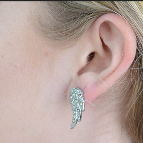 Close-up of an ear wearing a sparkling wing-shaped earring.