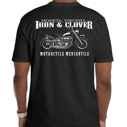 A man wearing a black Iron & Clover T-shirt with a graphic of a motorcycle on it. The shirt has text on the back mentioning 'Moneta Virginia Iron & Clover Motorcycle Mercantile'.
