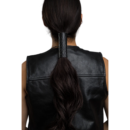 A person wearing a black leather hair glove with a debossed flames pattern.