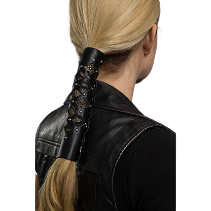 A person with blonde hair styled with a black leather hair glove featuring diamond cut-out pattern and lace details.