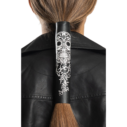 A person wearing a black leather jacket and a ponytail holder with a tribal skull design in white.