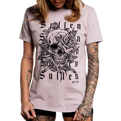A female model wearing a light purple t-shirt with a graphic of a skull and roses.