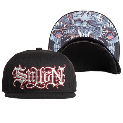 A black snapback cap with silver and red embroidered letters on the front and a printed artwork underside the brim, part of the Artist Series.