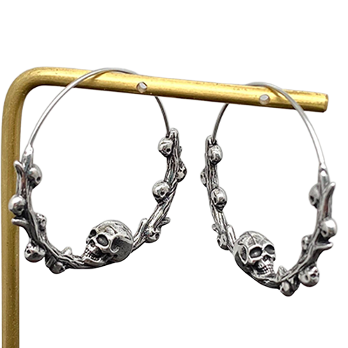 Silver hoop earrings with skull designs on a gold stand against a white background