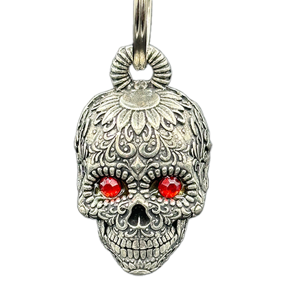 A silver-colored sugar skull bell with intricate designs and ruby-like jeweled eyes, attached to a metal split ring.