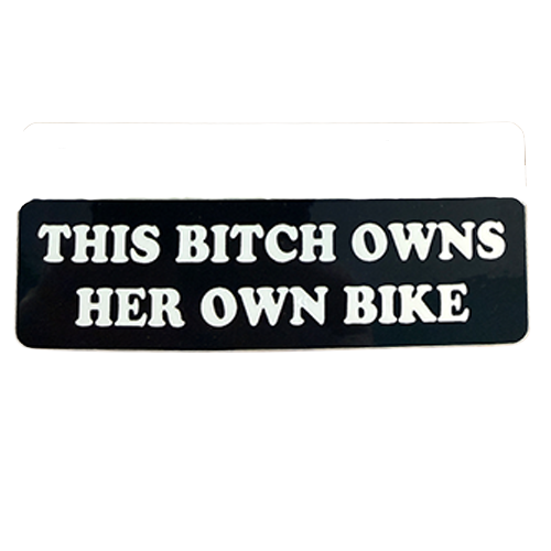 Black and white sign with text 'THIS BITCH OWNS HER OWN BIKE' on a white background